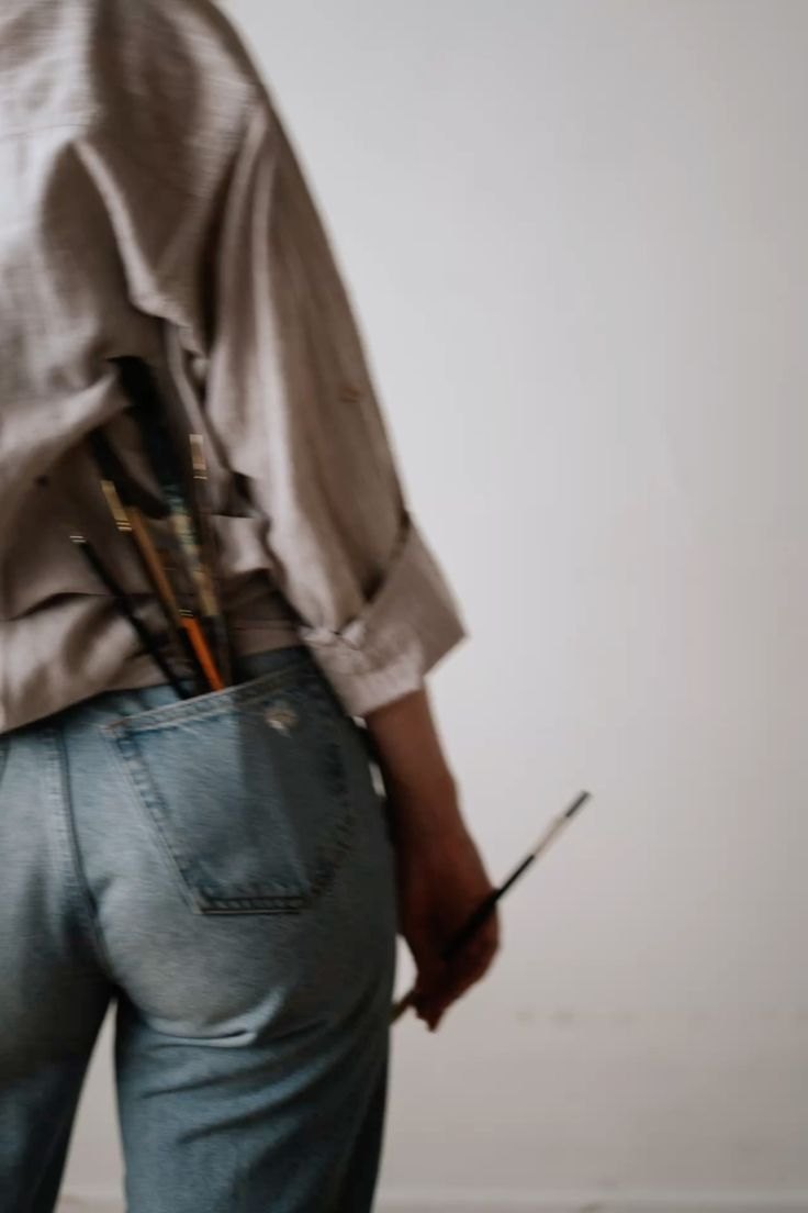 Artist with paintbrushes tucked in their back pocket