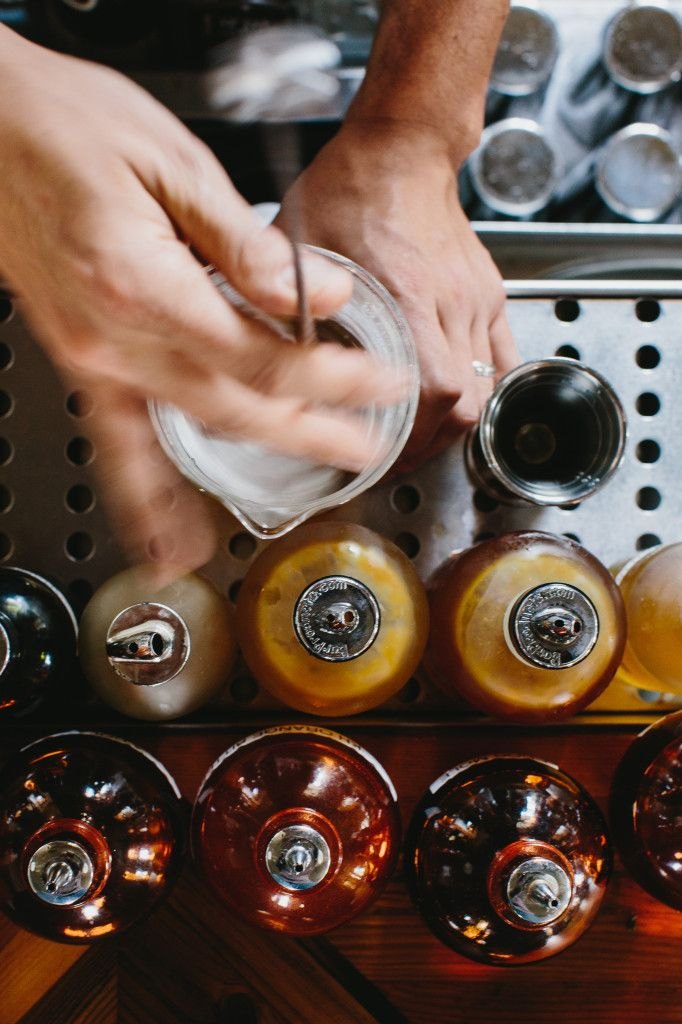 Bartender's hands building a cocktail over a row of bottles
